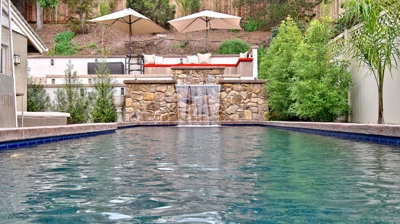 A backyard pool with a waterfall in the background Photo